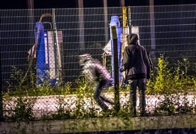 Migrantes superam barreira e tentam alcançar o terminal do Eurotúnel em Frethun a 6 de Agosto (Foto de Philippe Huguen/AFP/Arquivos)