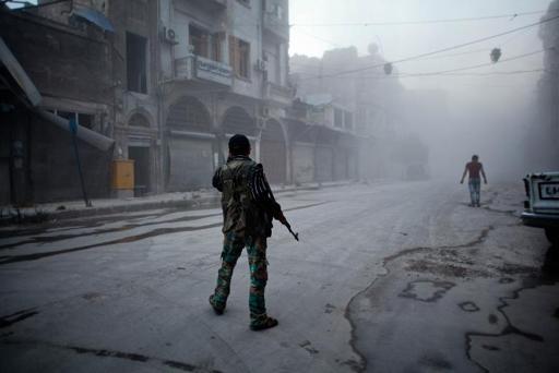 Um rebelde moderado mantém posição em meio à fumaça depois de um suposto ataque aéreo do Exército sírio em Aleppo, em julho de 2014 (Foto de Ahmed Deeb/AFP/Arquivos)