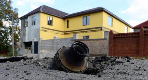 Cratera deixada por um foguete que atingiu uma rua de um bairro próximo do centro de Donetsk (Foto de JOHN MACDOUGALL/AFP)